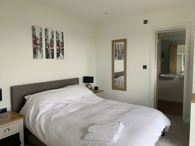 Bedroom 1: a bed with white linen, bedside lamps and artwork.