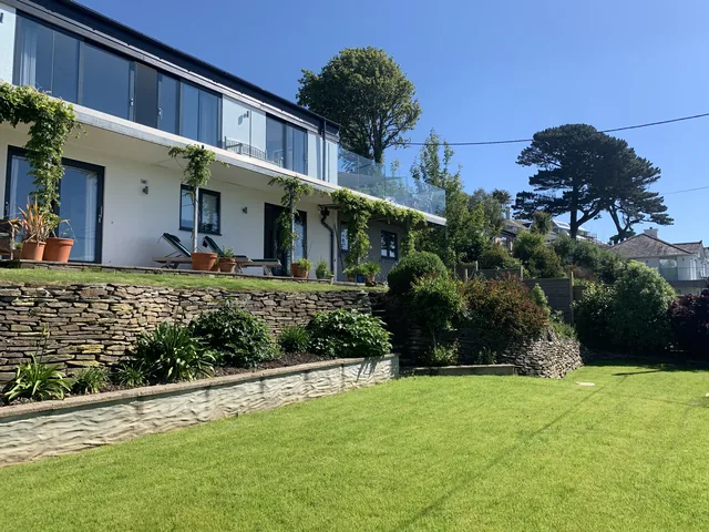 The house above the lawn, with planted terraces and stone retaining walls.