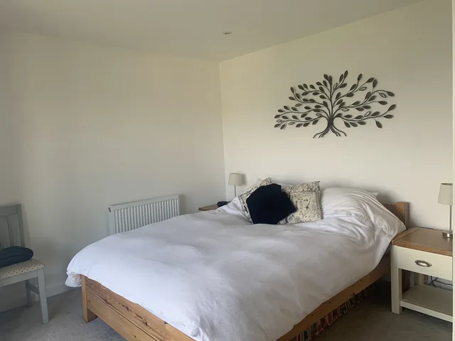 Bedroom 3: a bed with white linen beneath a metal tree decoration.